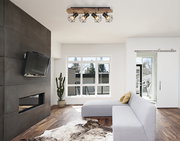 Deckenstrahler mit vier geometrischen Lampenschirmen aus schwarzem Metall, montiert auf einem Holzbalken, in einem modernen Wohnzimmer von unten betrachtet.