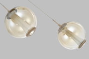 Twee moderne hanglampen met bolvormige, champagnekleurige glazen kappen en beige details, schuin van onderen gezien