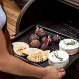 Nahaufnahme einer BBQ Grillplatte mit Feigen, Fladenbrot und Camembert auf einem Grill.