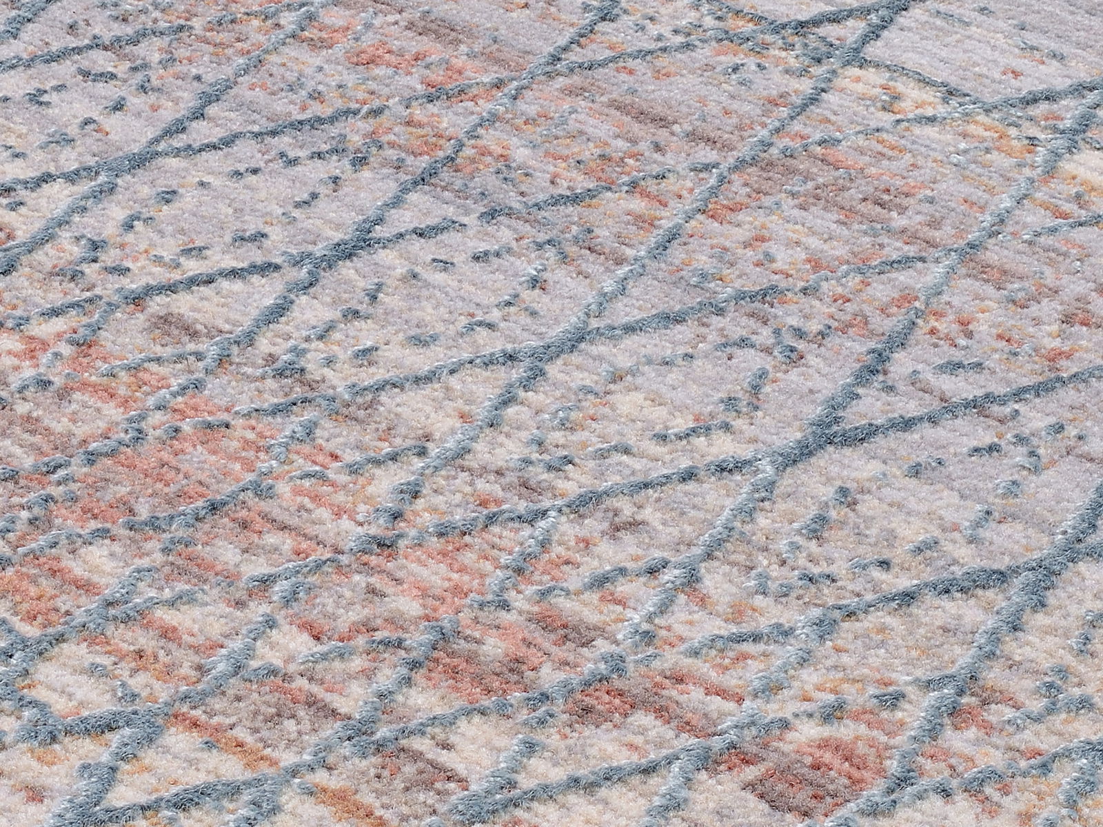 Nahaufnahme eines Designer-Teppichs mit geometrischem Muster in Pastellfarben, schräg von der Seite fotografiert.