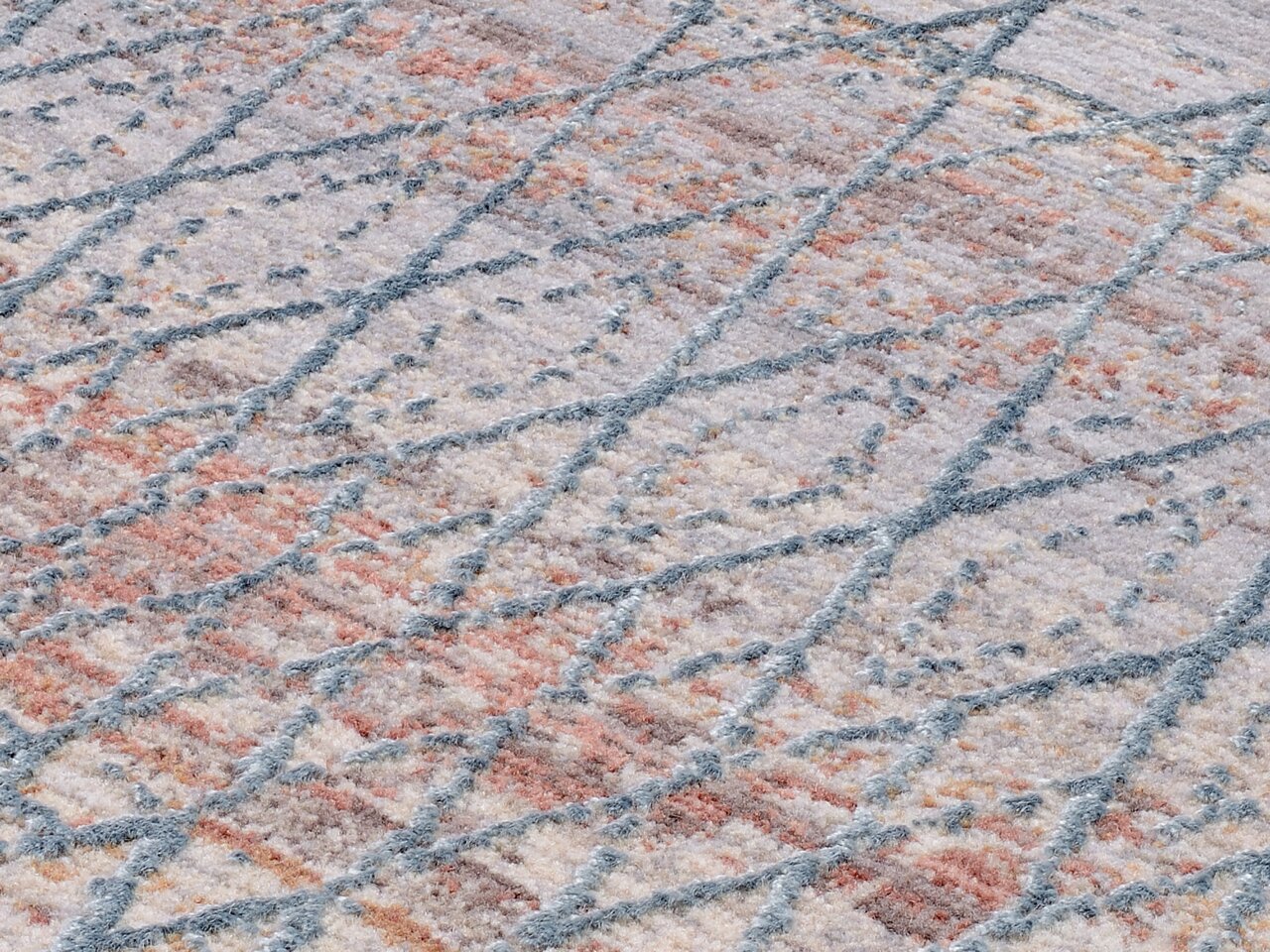 Nahaufnahme eines Designer-Teppichs mit geometrischem Muster in Pastellfarben, schräg von der Seite fotografiert.