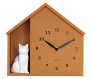 Wandklok in de vorm van een huisje met een wit kattenfiguurtje, van voren afgebeeld.