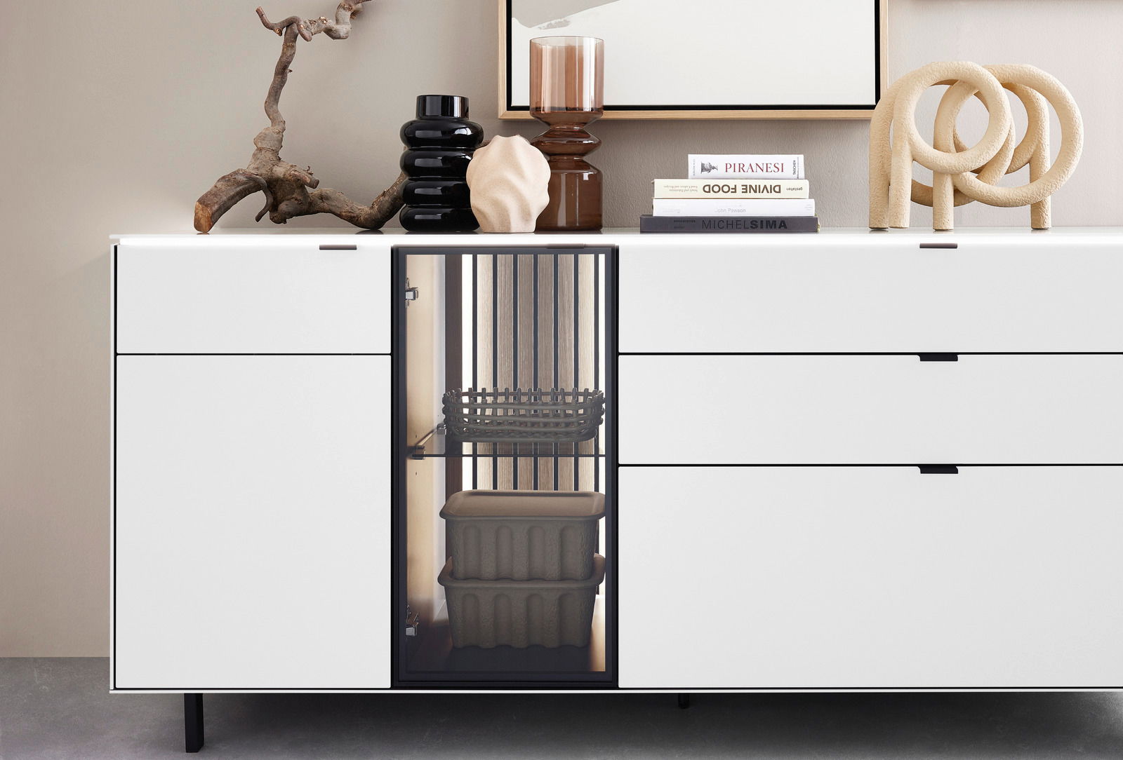 Modernes weißes Sideboard mit dekorativen Objekten und Büchern auf der Oberseite, frontal betrachtet.