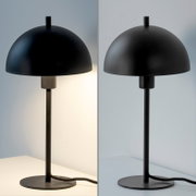 Schwarze, minimalistische Tischlampe mit halbrundem Schirm, schlankem Stab und rundem Standfuß, frontale Ansicht auf neutralem Hintergrund (links eingeschaltet, rechts ausgeschaltet).