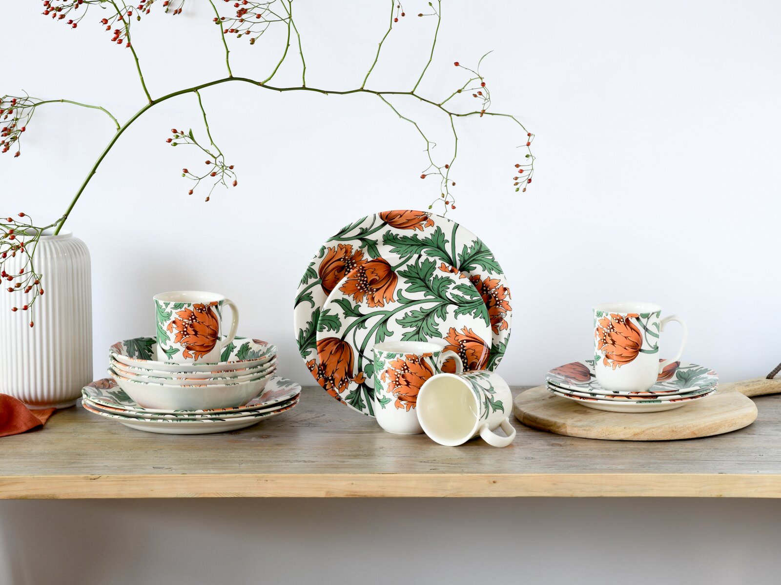 Creatable Kombiservice 16-tlg FLORENTINA Blumig gemustertes Keramik-Geschirrset in Weiß mit orangefarbenen Blüten und grünen Blättern, bestehend aus Tellern, Schalen und Tassen, auf einem Holztisch arrangiert; Perspektive: frontale Ansicht auf Augenhöhe.