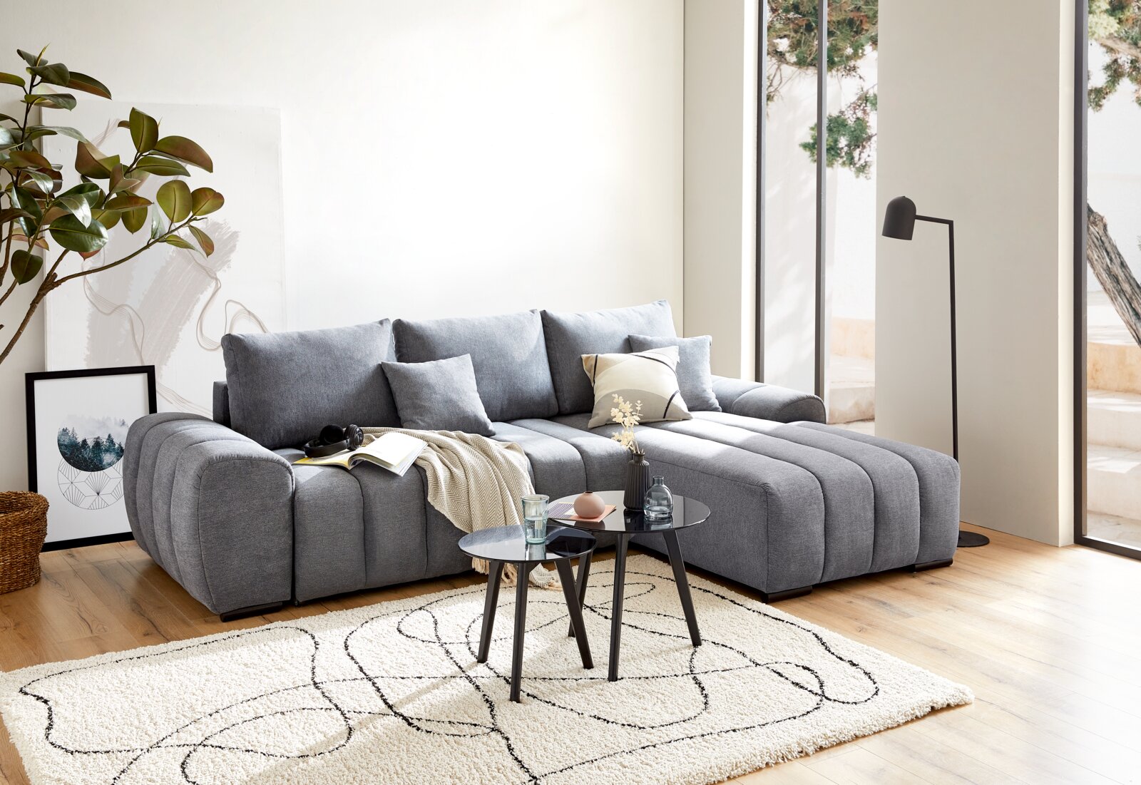 Z2 Ecksofa BARCA Graue Rundecke in modernem Wohnzimmer, seitliche Perspektive, mit Kissen und Couchtisch auf hellem Teppich.