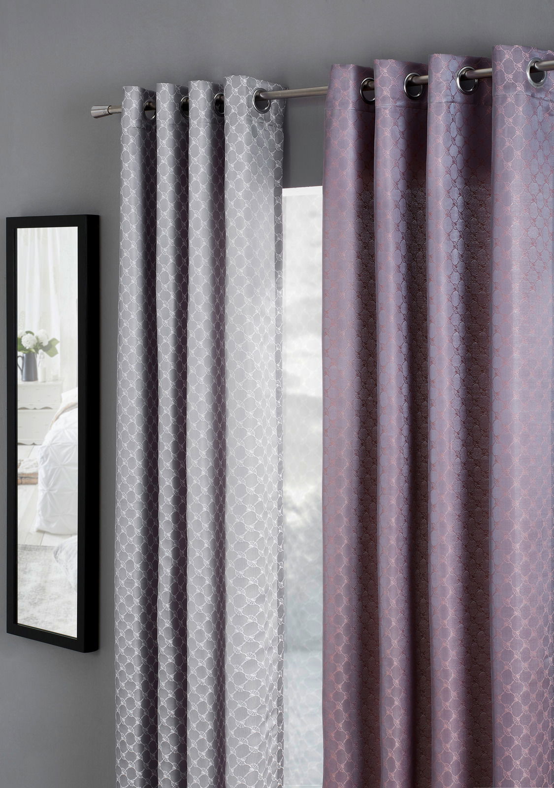 JOOP! Ösenschal J!Allover Zwei Vorhänge in Grau und Lila mit geometrischem Muster, aufgehängt an einer Gardinenstange, seitliche Perspektive.