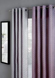 Zwei Vorhänge in Grau und Lila mit geometrischem Muster, aufgehängt an einer Gardinenstange, seitliche Perspektive.