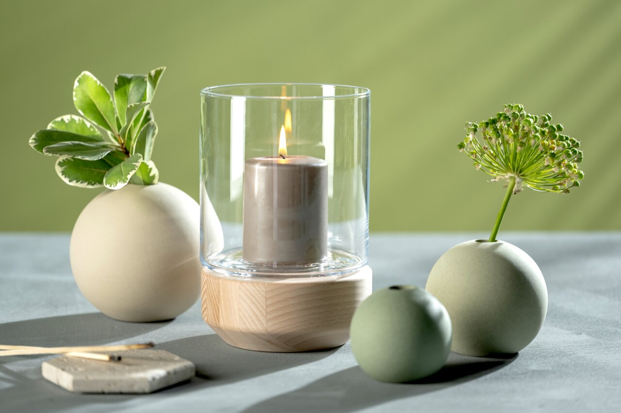 Keramische vaas in lichtgroen, bolvormig, met decoratieve planten, gefotografeerd vanuit een zijdelingse hoek.