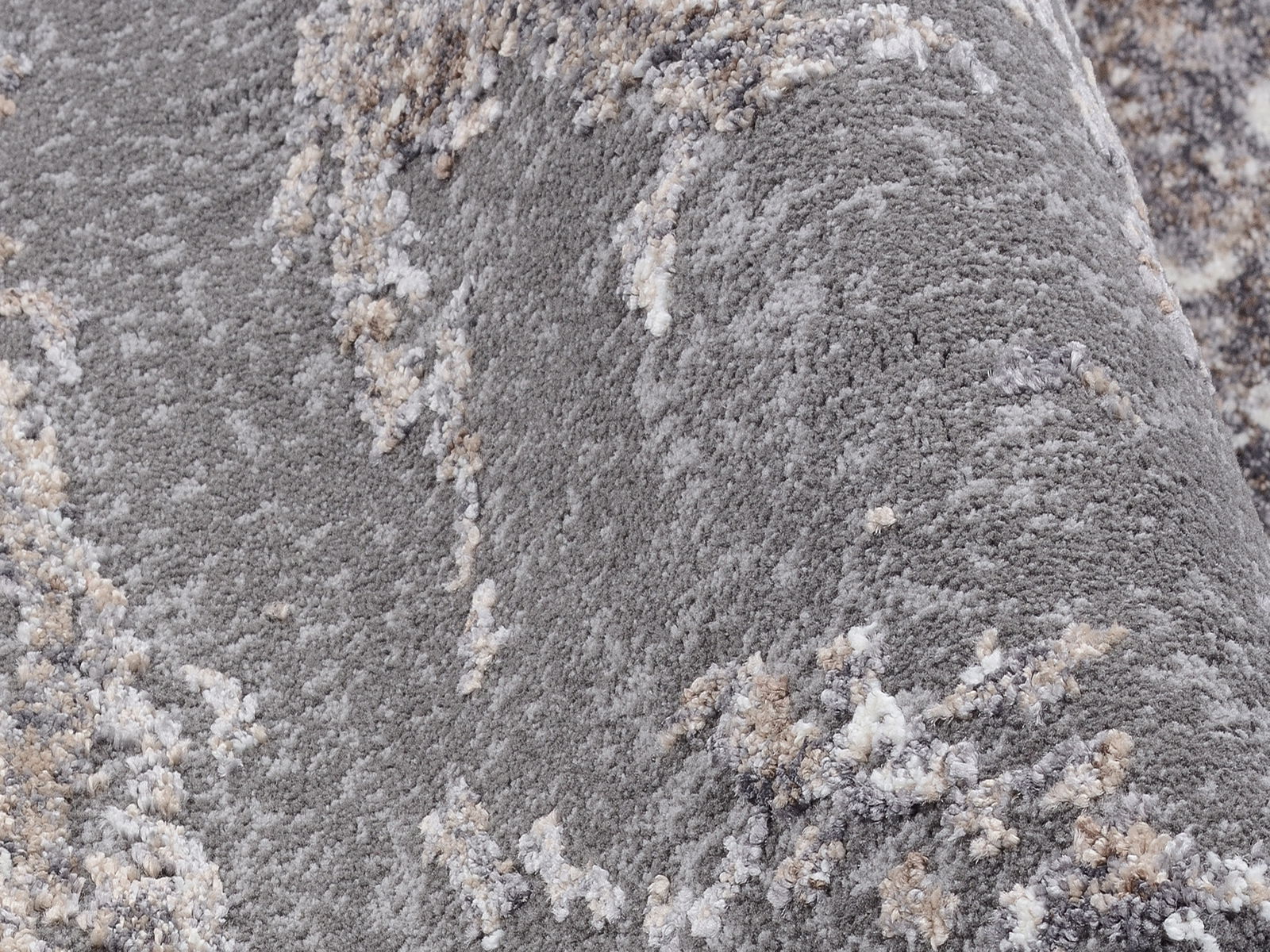 Nahaufnahme eines Designer Teppichs mit grauer und beiger Textur, seitliche Perspektive