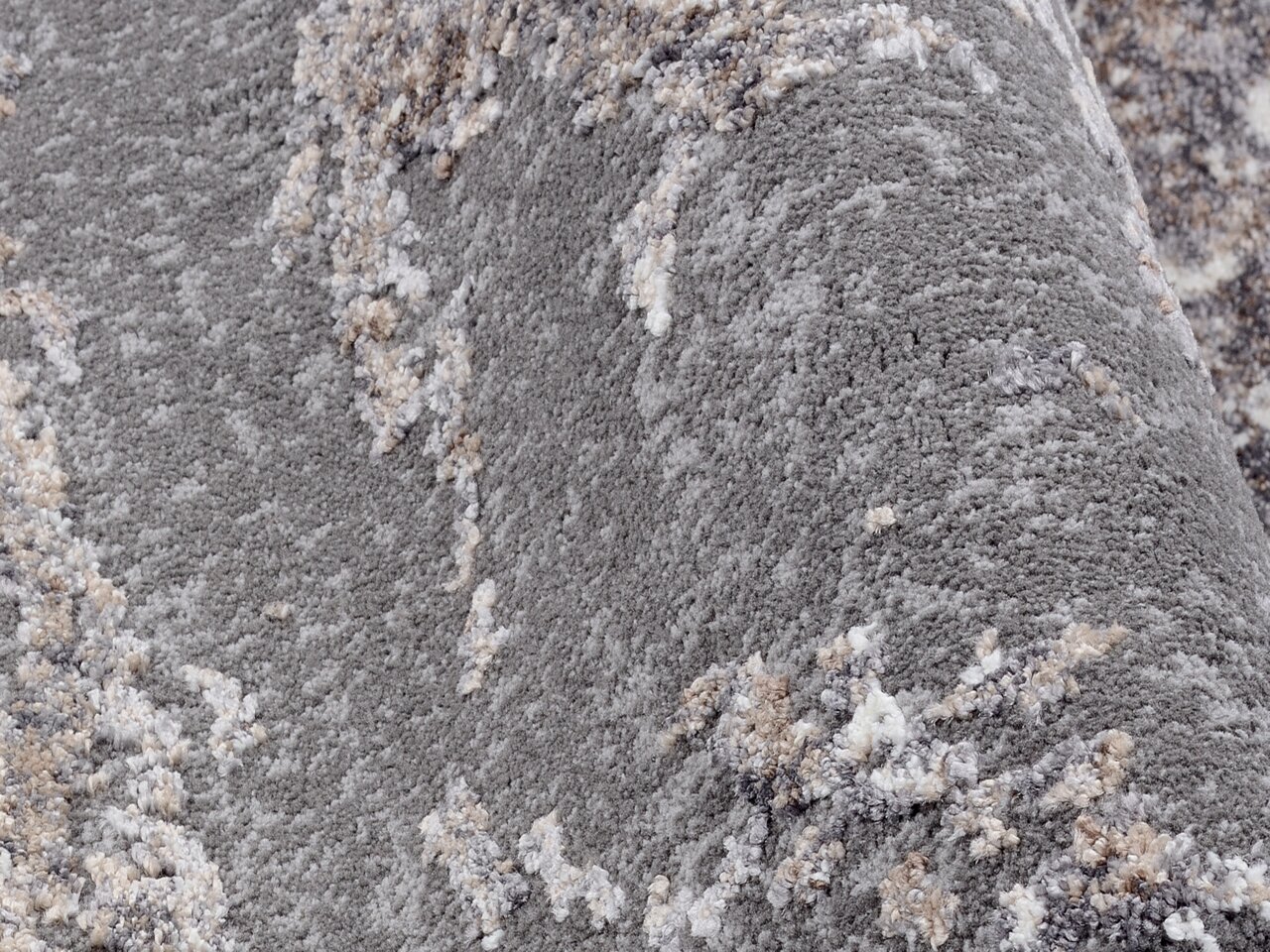 Nahaufnahme eines Designer Teppichs mit grauer und beiger Textur, seitliche Perspektive