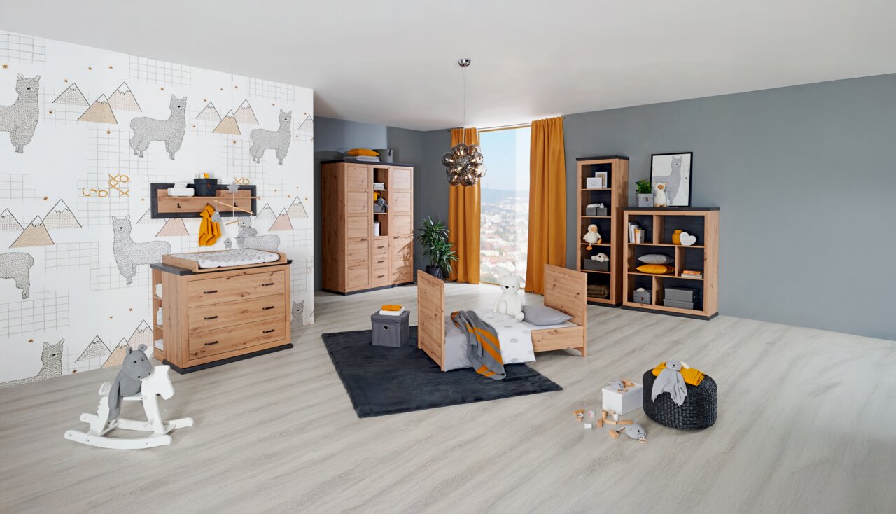 MyBaby Drehtürenschrank 2-türig BENTON Kinderzimmer mit Holzmöbeln, bestehend aus einem Kinderbett, einer Kommode mit Wickelaufsatz, einem Kleiderschrank und Regalen, in einer modernen, hellen Umgebung mit alpaka-gemusterter Tapete. Perspektive: Frontalansicht des gesamten Zimmers.