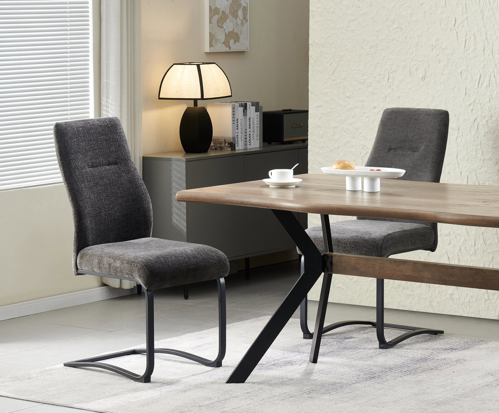 Modernes Esszimmer-Set mit Holztisch und schwarzem Metallgestell sowie zwei grauen Polsterstühlen, seitliche Perspektive im Wohnraum mit Lampe und Sideboard im Hintergrund