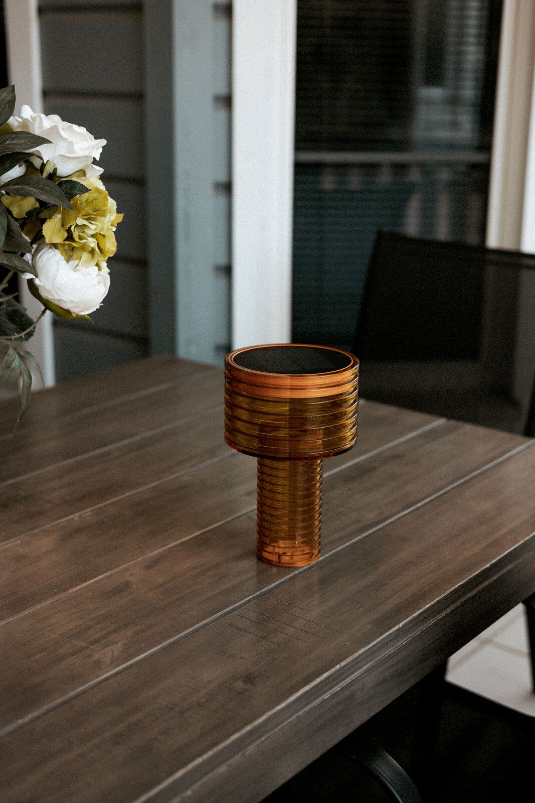 Akku-Solar-Tischleuchte in bernsteinfarbenem Design auf einem Holztisch, seitliche Perspektive.