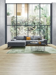 Graue Rundecke OttliZ2 FIGARO in modernem Wohnzimmer mit großem Fenster im Hintergrund, seitliche Perspektive.