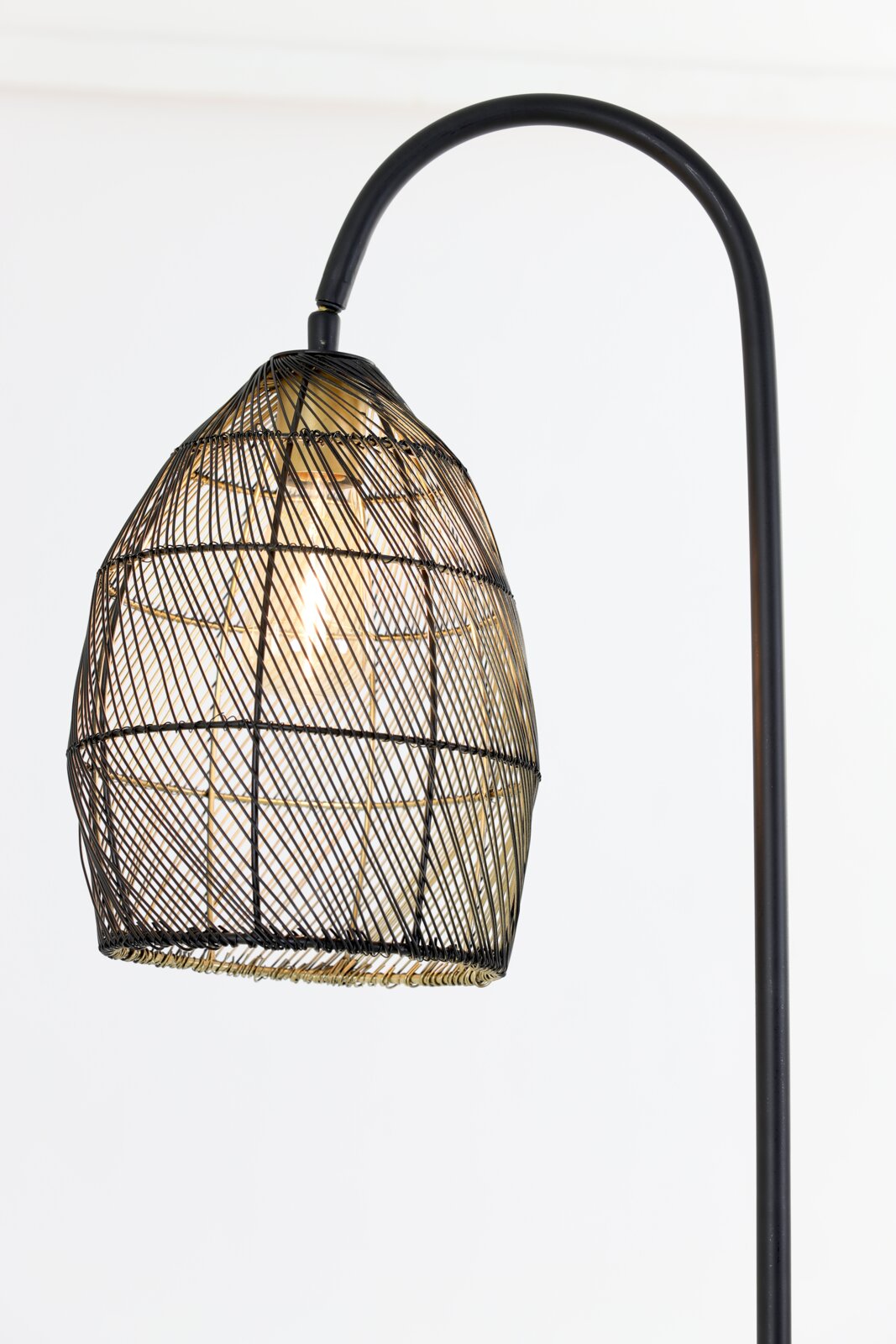 Detailaanzicht van voren van een zwarte booglamp met een open, gevlochten draadkap en warm brandende lichtbron