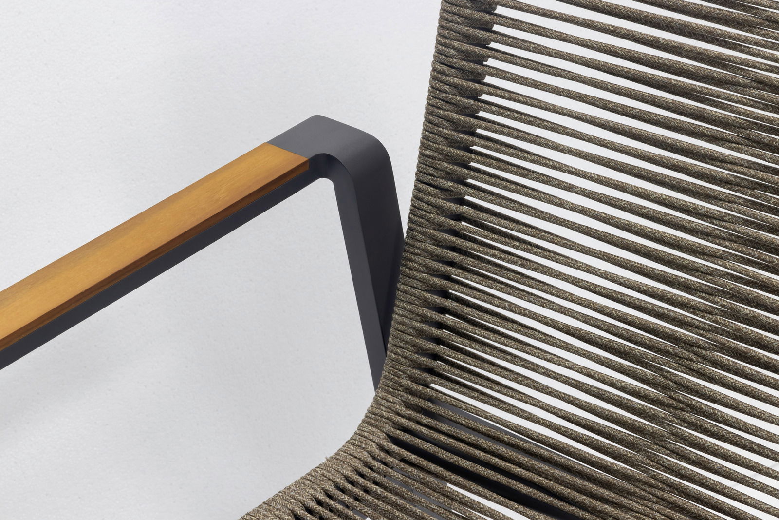 Nahaufnahme eines Stapelsessels mit einem modernen Design, das eine Kombination aus Holzarmlehne und geflochtenem Sitz zeigt, seitliche Perspektive.