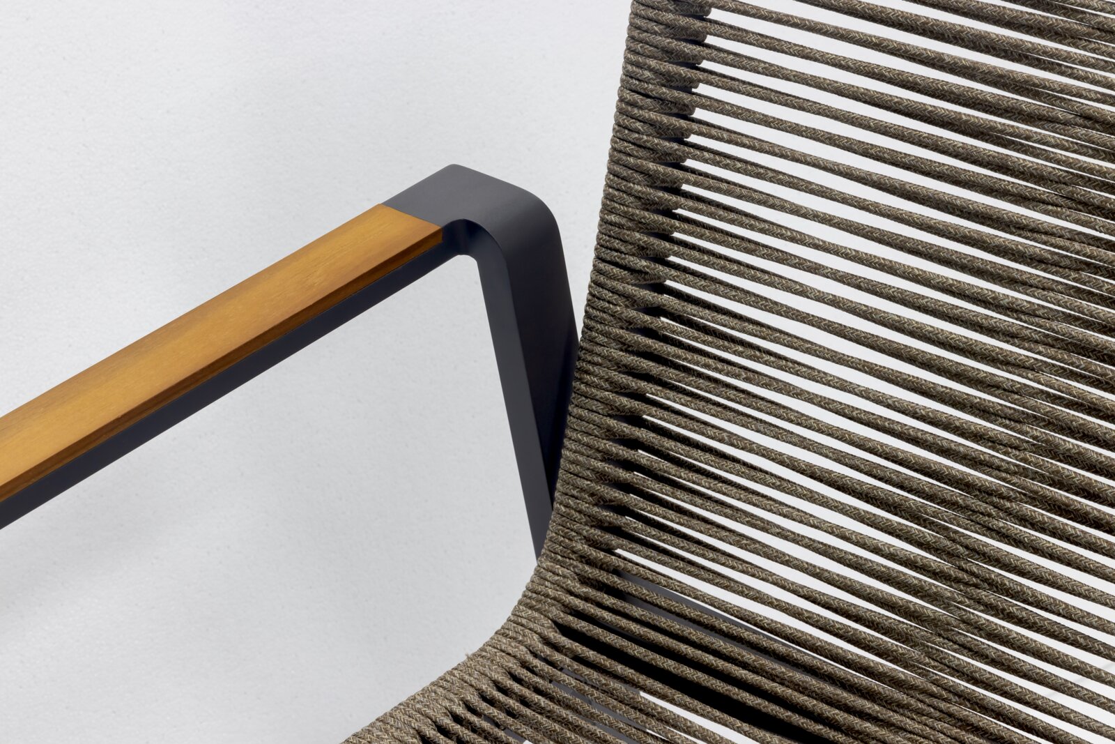 Close-up van een stapelstoel met een modern ontwerp, te zien is een combinatie van houten armleuningen en een gevlochten zitting, gezien vanuit de zijkant.