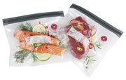 Zwei Vakuumbeutel mit frischem Lachs und Fleisch, von oben fotografiert, mit Kräutern und Zitronenscheiben garniert.