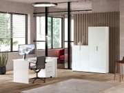 Moderner Büroraum mit weißem Schreibtisch, Bürostuhl und hohem Aktenschrank, seitliche Perspektive.
