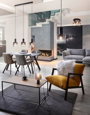 Moderne Wohnzimmeransicht mit Hängeleuchten über einem Esstisch, einer Tischleuchte auf einem Couchtisch und einer Deckenleuchte, Perspektive von vorne.