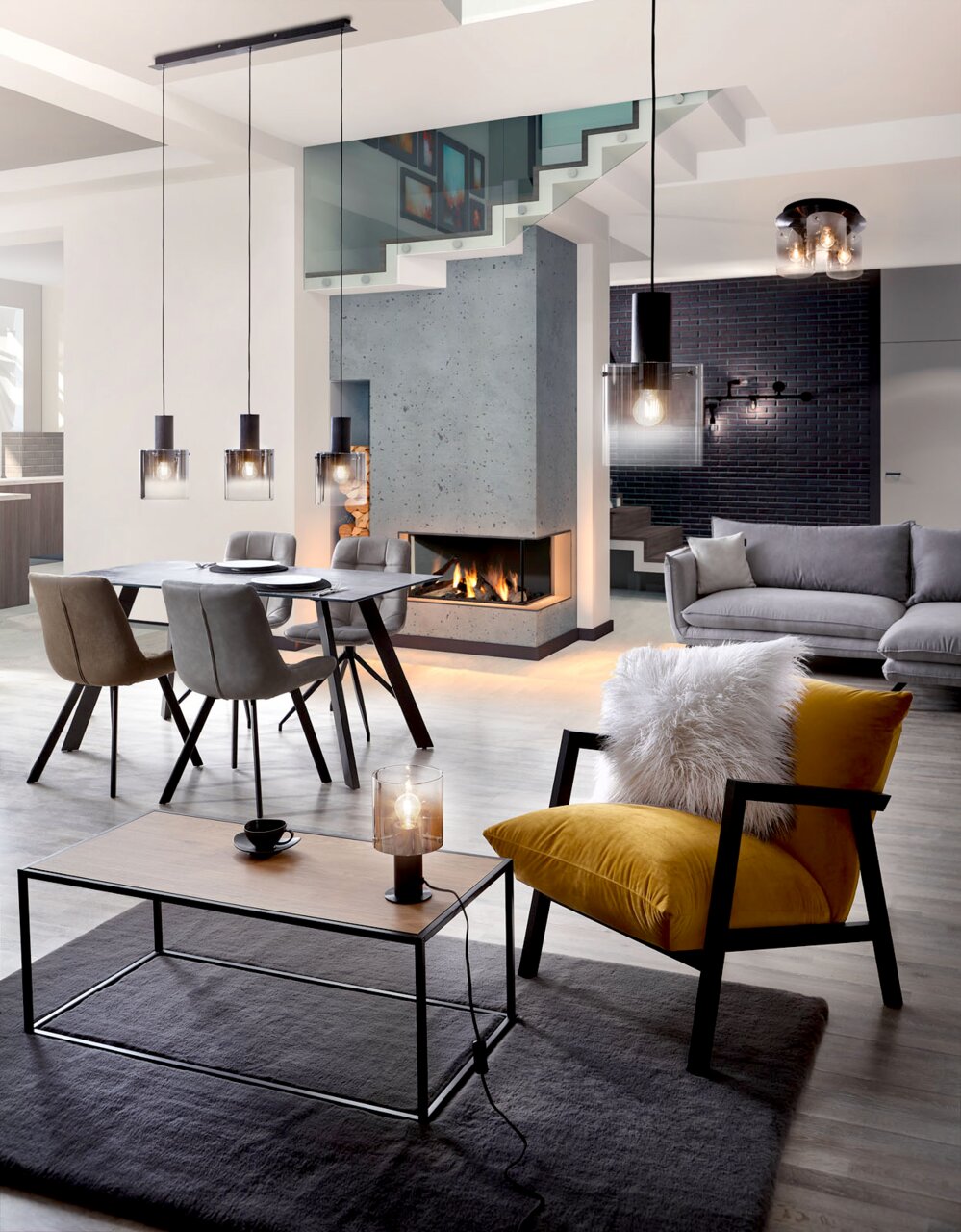 Brilliant Leuchten Deckenleuchte BETH Moderne Wohnzimmeransicht mit Hängeleuchten über einem Esstisch, einer Tischleuchte auf einem Couchtisch und einer Deckenleuchte, Perspektive von vorne.