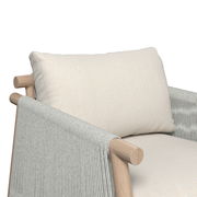 Nahaufnahme eines Lounge-Sessels mit hellem Kissen und Holzarmlehnen, seitliche Perspektive.