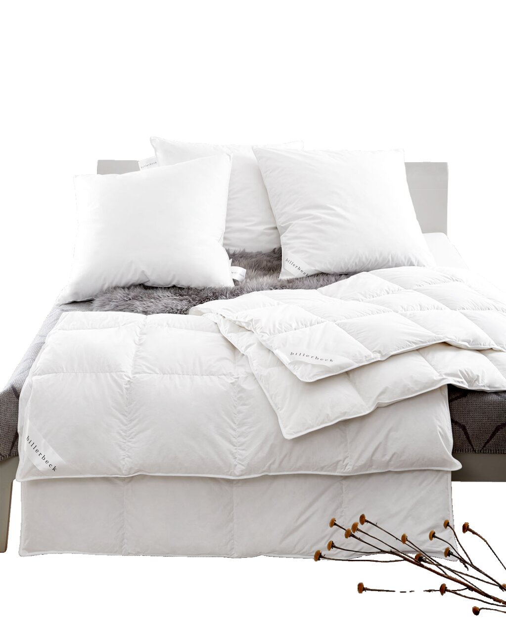 Een blik op een bed met witte donzen kussens en een donzen dekbed, versierd met een grijze bontsprei.