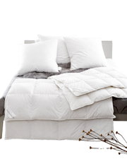 Een blik op een bed met witte donzen kussens en een donzen dekbed, versierd met een grijze bontsprei.