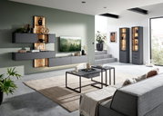 Moderne Wohnzimmer-Wandkombination in dunklem Grau mit Holzakzenten, bestehend aus mehreren Hängeschränken und einem TV-Board, stilvoll dekoriert. Perspektive von der Seite mit Blick auf die gesamte Wohnwand.