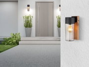 Moderne Außenleuchte mit Holz- und Glaselementen, seitliche Perspektive auf eine Hauswand montiert.
