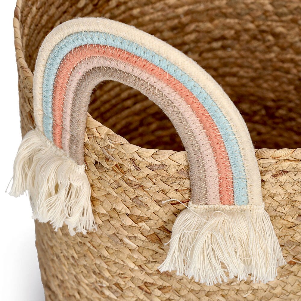 Nahaufnahme eines geflochtenen Aufbewahrungskorbs mit einem bunten Regenbogengriff und Fransen, aus seitlicher Perspektive.