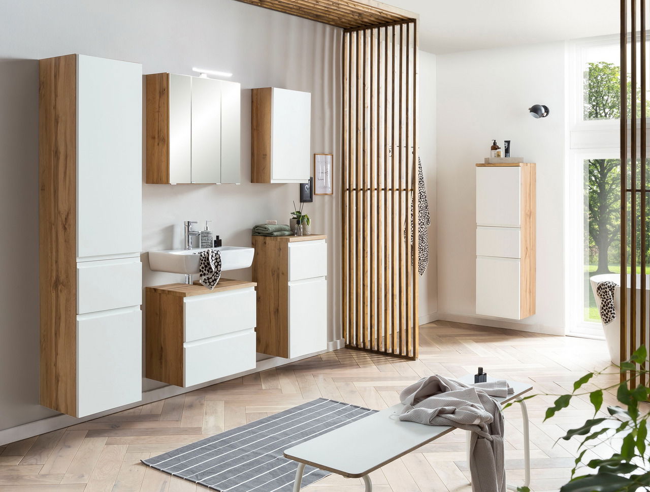 Moderner Hochschrank in Holzoptik mit weißen Fronten, Teil eines stilvollen Badezimmersets, aus der Perspektive von vorne links aufgenommen.