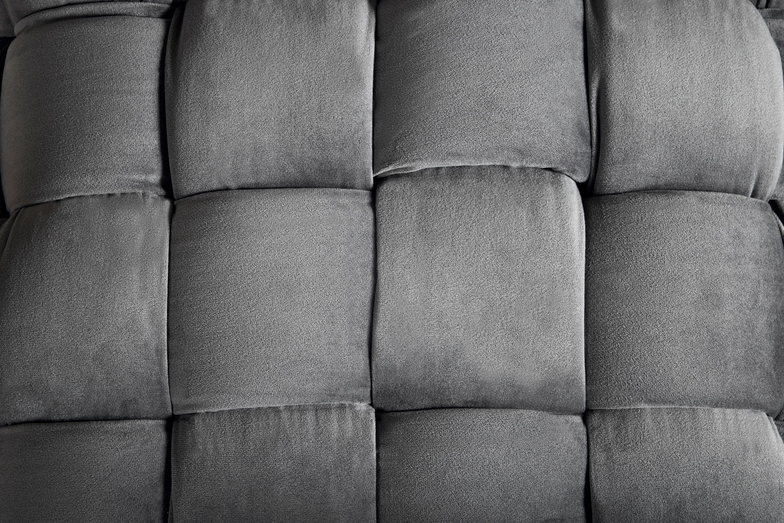 Nahaufnahme eines grauen, gepolsterten Hockers mit quadratischem Muster, von oben betrachtet.