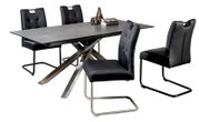 Moderne uitschuifbare eettafel met donkergrijs blad en metalen X-poot, met vier zwarte gestoffeerde sledestoelen, schuin van voren gefotografeerd