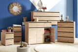 Moderne Holzkommoden in verschiedenen Größen, frontal fotografiert, vor einer blauen Wand mit dekorativem Spiegel.
