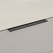 Detailaufnahme eines Schubladengriffs in mattem Schwarz an einer hellgrauen Schubladenfront, schräg von oben fotografiert