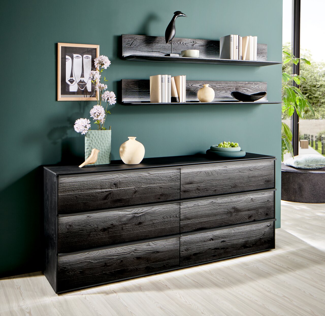 Modernes Sideboard aus dunklem Holz mit sechs Schubladen, dekoriert mit Vasen und Pflanzen, seitliche Perspektive.