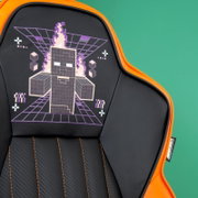Gaming-Stuhl mit schwarzer und orangefarbener Polsterung, verziert mit einem pixeligen, flammenumhüllten Charakter auf der Rückenlehne, aus frontaler Perspektive.