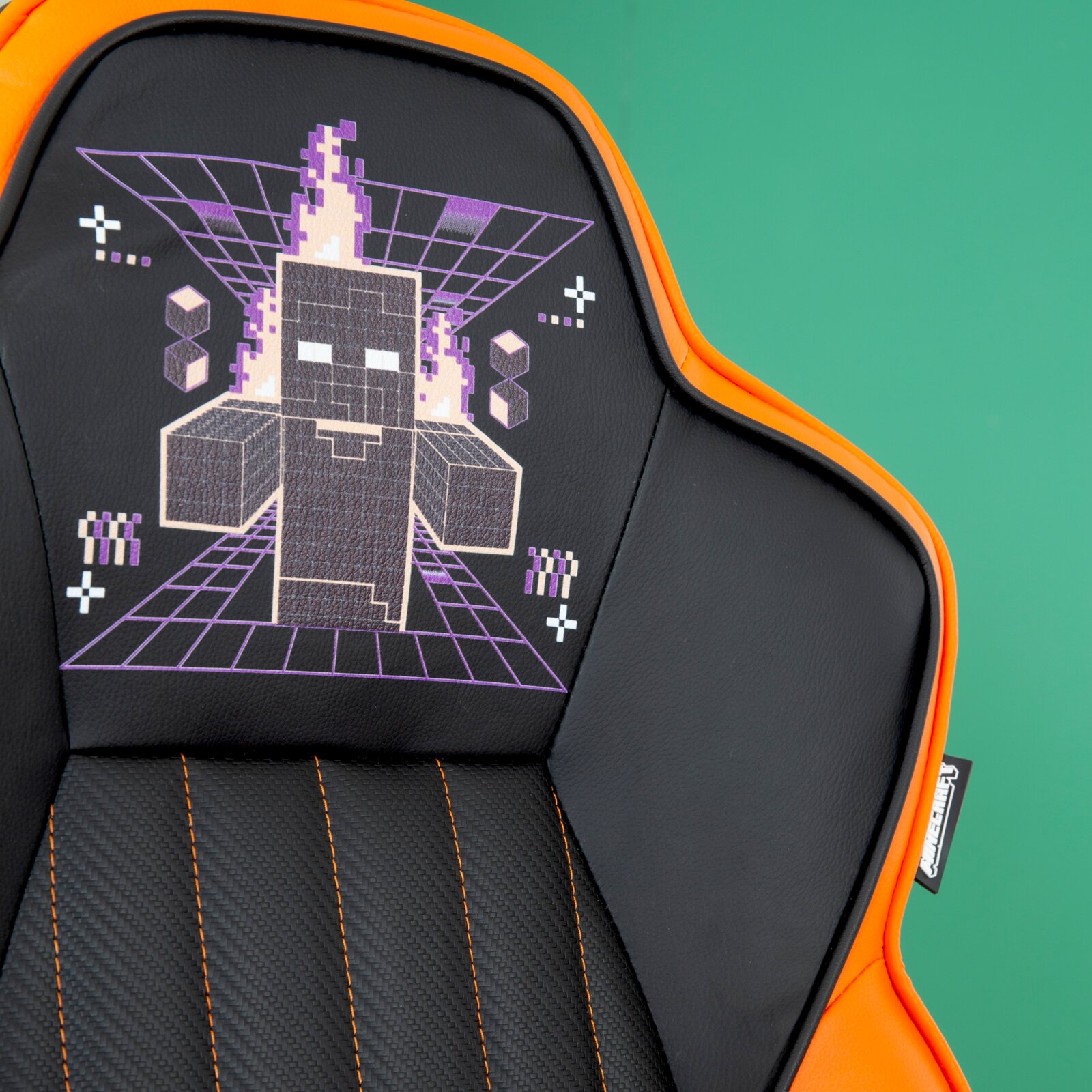 Gamingstoel met zwarte en oranje bekleding, versierd met een gepixeld, door vlammen omgeven personage op de rugleuning, gezien vanuit het vooraanzicht.