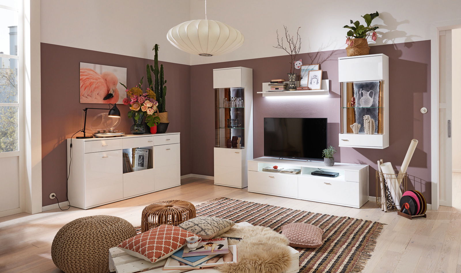 Modernes Wohnzimmer mit TV-Lowboard in Weiß, umgeben von stilvollen Regalen und Dekorationen, aus der Perspektive von vorne betrachtet.