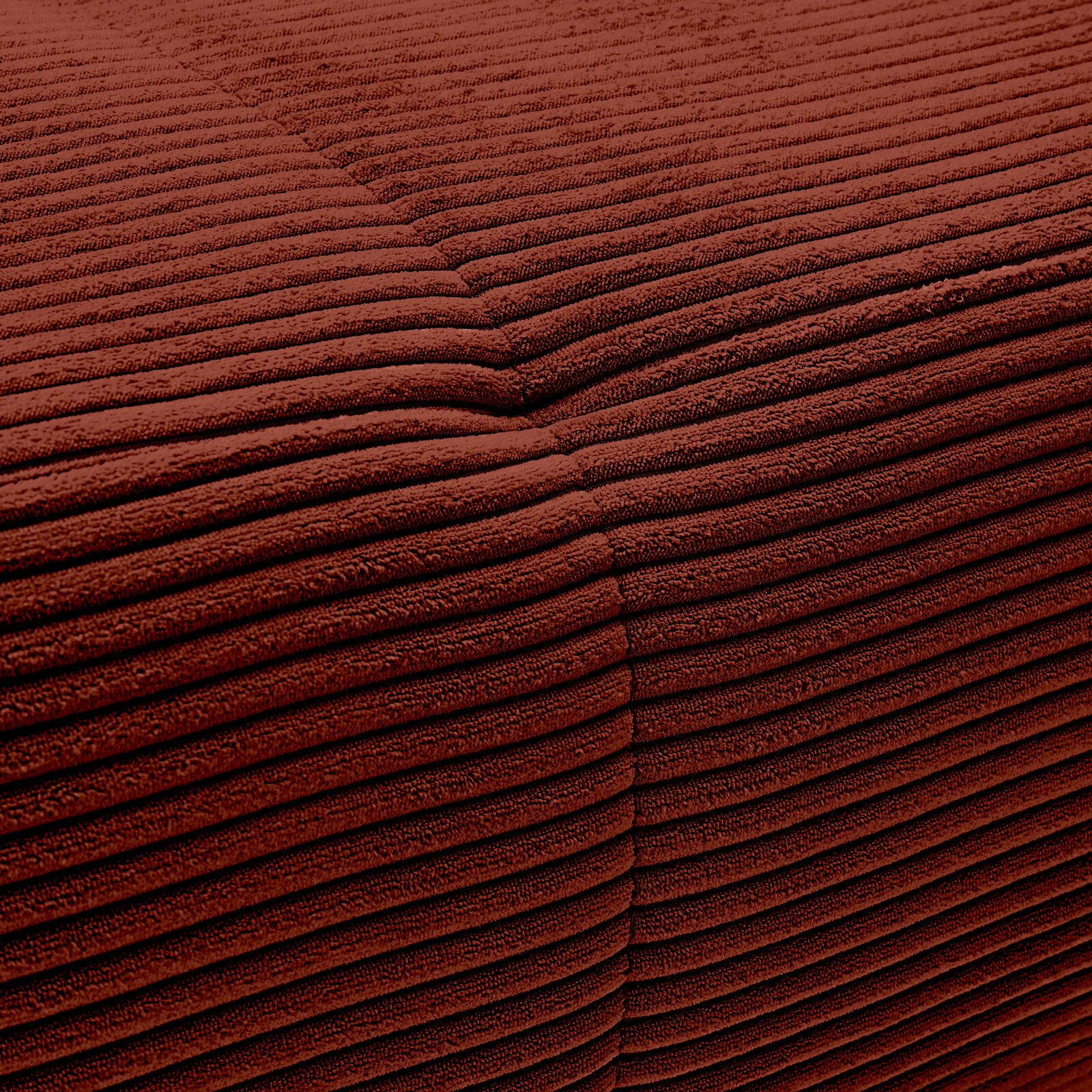 Nahaufnahme einer rotbraunen, gerippten Stoffoberfläche mit sichtbarer Naht.