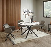 Moderner Esstisch mit rundem, weißem Tischblatt und schwarzen, gekreuzten Beinen, umgeben von drei gepolsterten Stühlen in einem stilvollen Esszimmer. Perspektive: Frontalansicht.