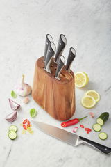 Vogelperspektive auf einen Messerblock aus Holz mit sieben Messern, umgeben von frischen Zutaten wie Zitrone, Knoblauch, Zwiebel und Chili auf einer Marmoroberfläche.