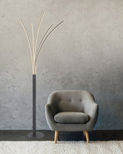 Moderne Stehleuchte aus schwarzem Metall mit geschwungenen Lichtarmen, neben einem grauen Sessel in einem Wohnzimmer. Frontalansicht.