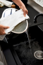 Topfset 5tlg. True Flow in der Küche, Wasser wird aus einem Topf in die Spüle gegossen, seitliche Perspektive