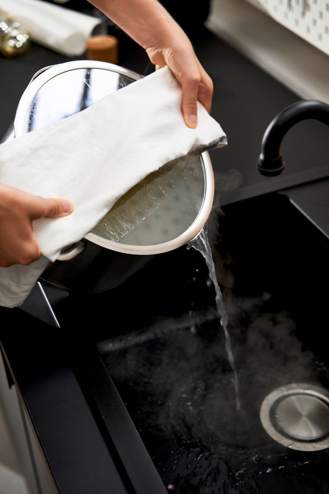 Topfset 5tlg. True Flow in der Küche, Wasser wird aus einem Topf in die Spüle gegossen, seitliche Perspektive