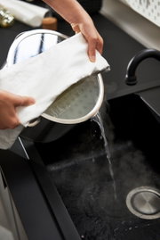 5-delige pannenset True Flow in de keuken, water wordt uit een pan in de gootsteen gegoten, zijaanzicht