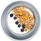 Grauer Teller mit Müsli, Joghurt, Blaubeeren und Physalis, von oben betrachtet.