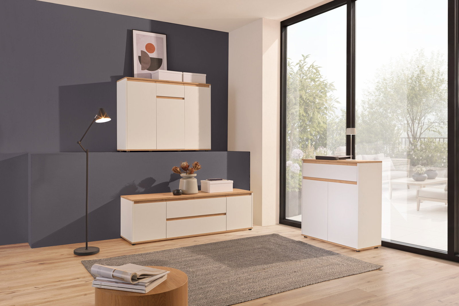 Carryhome Sideboard MALEA Modernes Sideboard-Set in einem hellen Raum mit großen Fenstern, bestehend aus einem hängenden und einem stehenden Element, in Weiß mit Holzdetails, aus der Perspektive eines Wohnzimmers.